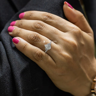 Close-up of a hand we 1 Carat Pear Shaped Moissanite Cluster Ring with a black background