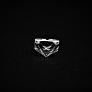 Back view of a Princess cut Moissanite resting on a black surface, showcasing its sharp pavilion and geometric faceting.