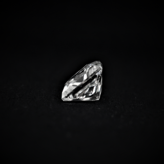 Side view of a Princess cut Moissanite gemstone on a black surface, highlighting its sharp facets and elegant profile.