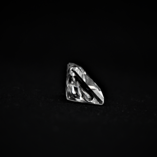 Side view of a Princess cut Moissanite gemstone on a black surface, highlighting its sharp facets and elegant profile.
